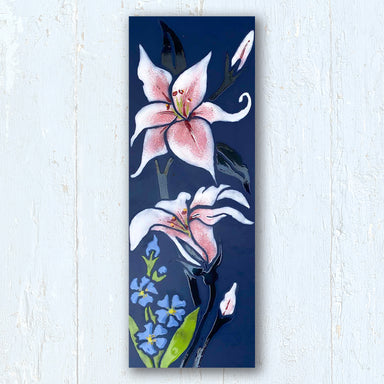 Hand drawn and hand glazed image of a Stargazer lily with blue Forget-Me- Not flowers on a dark cobalt blue porcelain tile