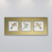 A trio of three different delicately coloured hummingbirds on beige porcelain tile mounted horizontally in a gold anodized aluminum frame