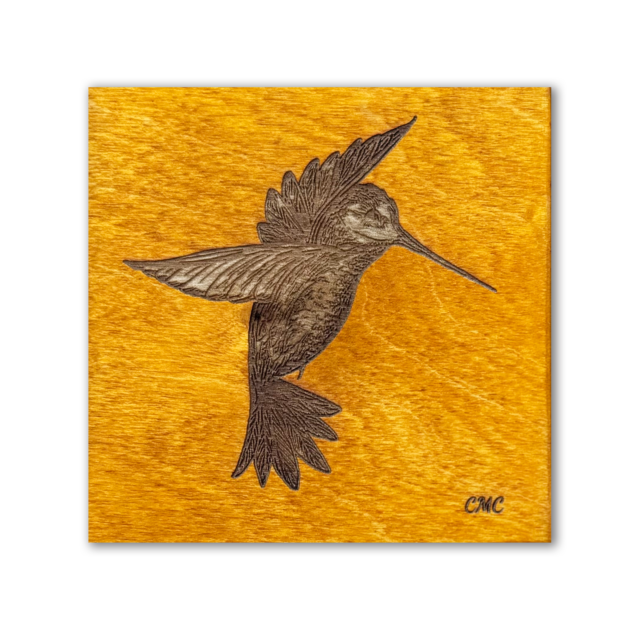 Laser engraved hovering hummingbird on amber stained baltic birch tile