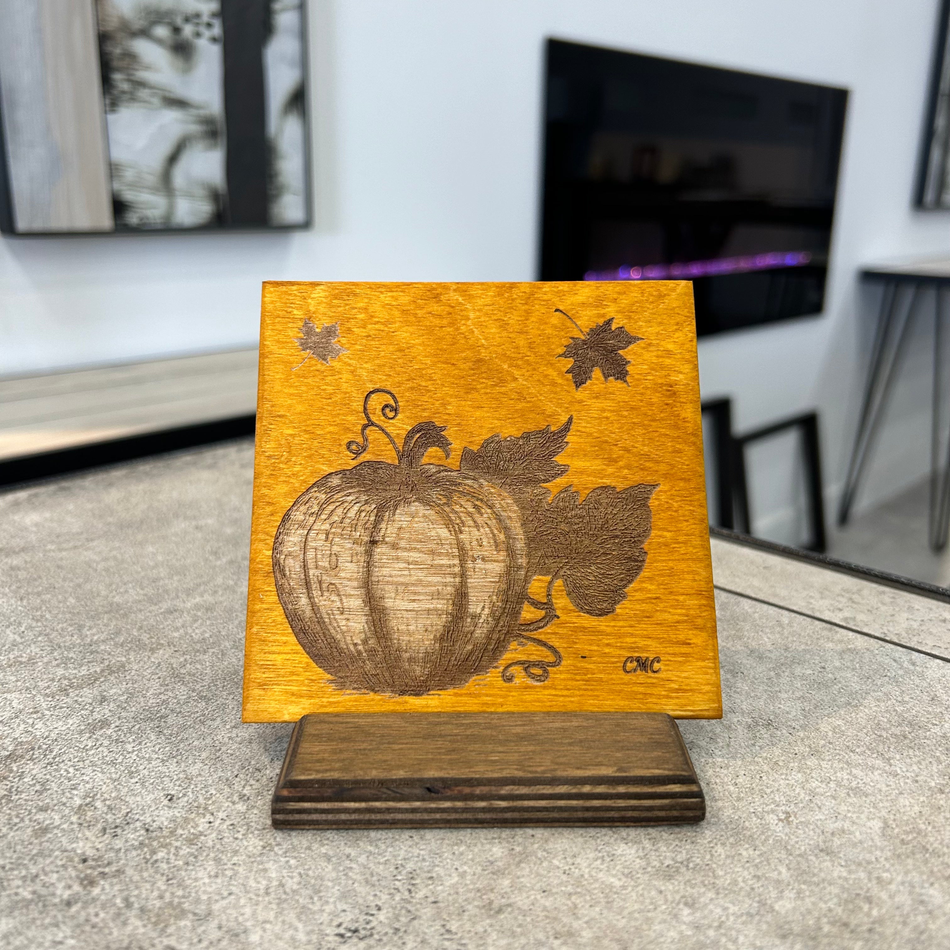 Laser engraved pumpkin image on a Baltic Birch amber stain tile. The tile is displayed on a Baltic Birch stand