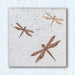 An art tile with a trio of three dragonflies on a beige porcelain tile